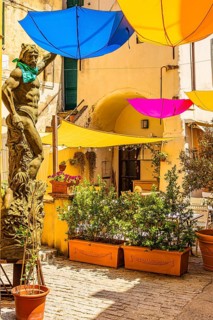 Coloured umbrellas cover a bronze statue in Via Cavour, Capoliveri, Elba Island, Tuscan Archipelago