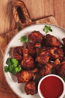 Juicy fried chicken pieces, served with spicy dipping sauce, on a rustic wooden table