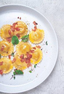 Fresh ravioli, with butter, spices and herbs, fried bacon, on the table, top view, light
