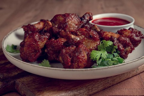 Juicy fried chicken pieces, served with spicy dipping sauce, on a rustic wooden table