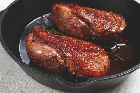 Roast duck breast, in a frying pan, with spices and herbs, close-up, no people