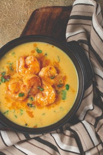 Creamy shrimp curry with spices, garnished with herbs, on a textured background, homemade, no