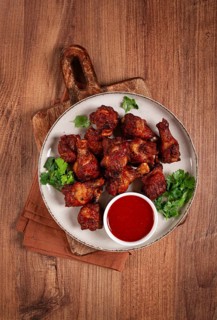 Juicy fried chicken pieces, served with spicy dipping sauce, on a rustic wooden table