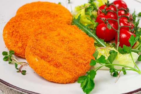 Crispy fried fish cutlets, fish burgers, on a white plate, with fresh lettuce leaves, arugula and
