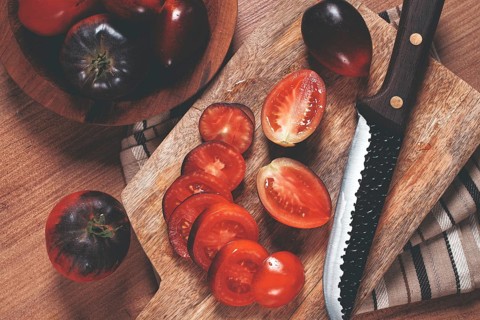 Sliced tomatoes, Black Beauty variety, on a cutting board, top view, on the kitchen table