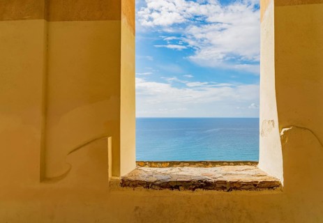 Sunny mediterranean sea scenery seen through a window opening in a historic wall seen in Liguria,