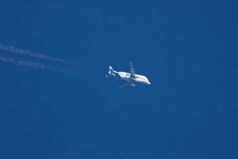 Airbus A300-600ST Super Transporter or Beluga aircraft in flight in a blue sky with vapour trails