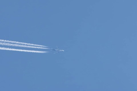 Boeing 747 Jumbo jet passenger aircraft in flight in a blue sky with vapour trails or contrails