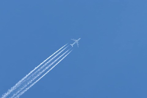 Airbus A340-300 jet aircraft of Lufthansa airlines in flight in a blue sky with vapour trails or