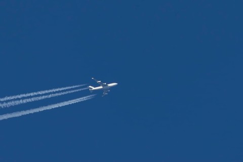 Boeing 747 Jumbo jet passenger aircraft in flight in a blue sky with vapour trails or contrails