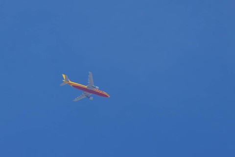 Boeing 767 jet aircraft of DHL cargo airlines in flight in a blue sky, England, United Kingdom