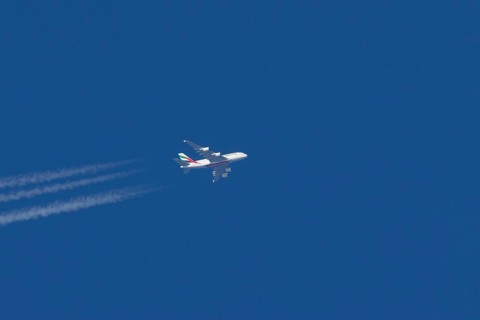 Airbus A380 jet passenger aircraft of Emirates airlines in flight in a blue sky with vapour trails