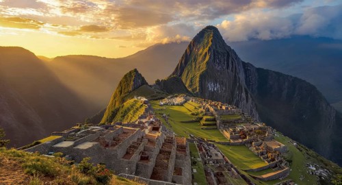 Dramatic landscape photo of Machu Picchu at sunrise, with the ancient Inca citadel illuminated by