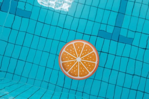 Blue swimming pool from above, an orange tray floats in it
