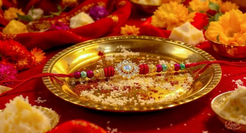 A close-up shot of a decorative rakhi placed on a golden plate with traditional Indian sweets and