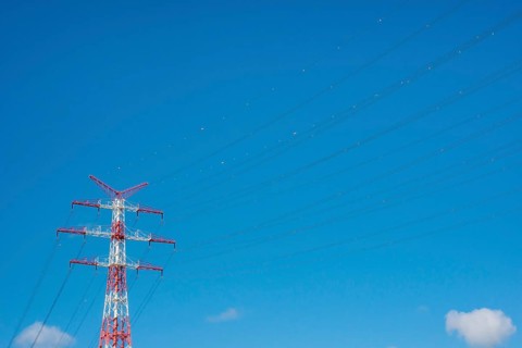 An extremely high electricity electricity electricity pylon, marked white and red, on the banks of