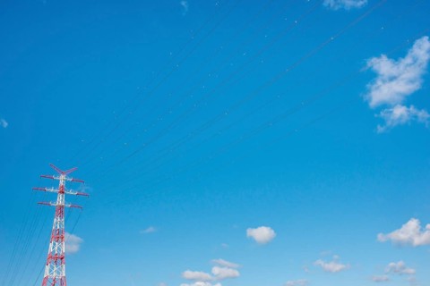 An extremely high electricity electricity electricity pylon, marked white and red, on the banks of