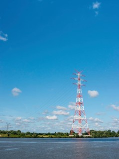 An extremely high electricity electricity electricity pylon, marked white and red, stands on the