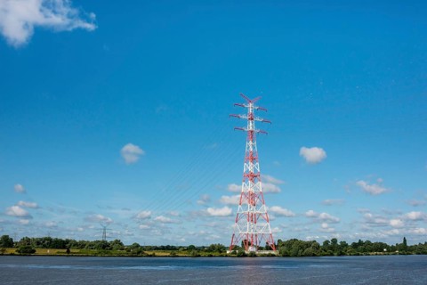 An extremely high electricity electricity electricity pylon, marked white and red, stands on the