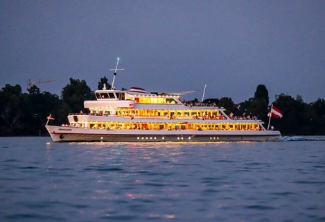 Brightly illuminated passenger ship VORARLBERG underway on Lake Constance during the blue hour.