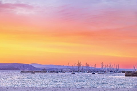 Marina with pleasure boats at a beautiful sunset over the sea and the rocky coastline a summer