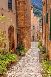 Empty cobblestone alley with beautiful stone houses a sunny hot day in an old spanish village,