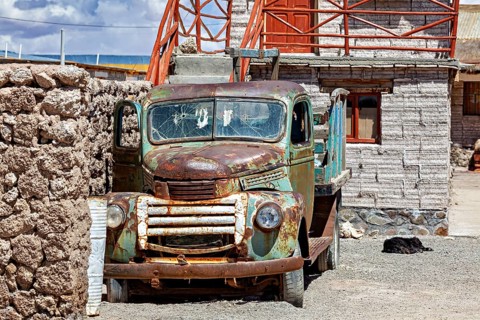Abandoned rusty lorry in front of a stone building in a peaceful desert landscape, Old lorry in a