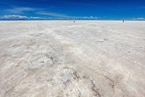 Endless salt desert under an azure blue sky, a solitary figure in the distance, The endless