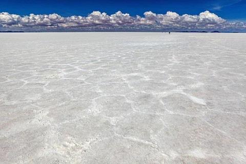 Salt crust with hexagonal patterns under a sky full of clouds, conveying endless expanses, The