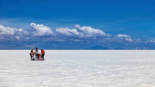 Group of people around a table on a vast white salt flat under a blue sky, The endless expanses of