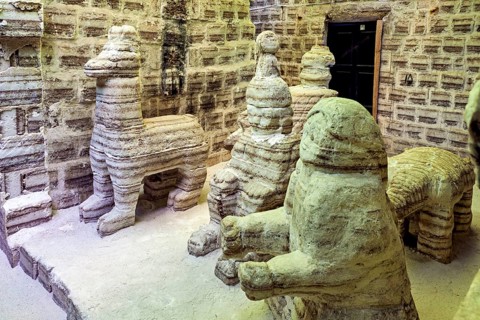 Beige stone sculptures of animals in a rustic room with patterned brick walls, The salt hotel in