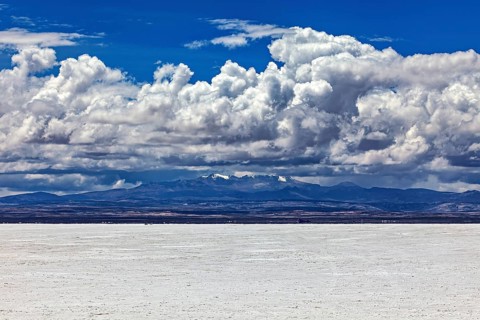 Scenic salt flat with dramatic clouds and distant mountain peaks on the horizon, The endless
