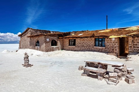 Rustic stone house in a desert-like landscape with blue sky and white ground, the salt hotel in the