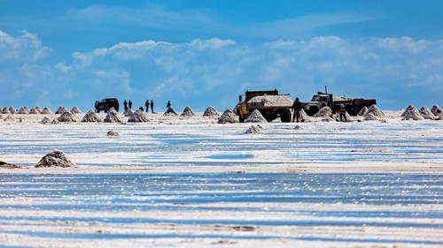 Vehicles and people move between salt hills on a shiny salt surface, The endless expanses of the