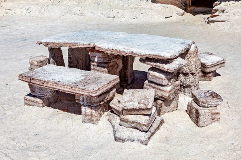 Rustic stone table with benches outdoors on a sandy, white surface, The salt hotel in the salt