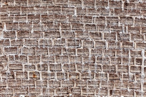 General view of a textured brick wall in earthy tones with an antique look, A wall made of salt