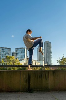 Young martial artist performing the crane pose in a modern city