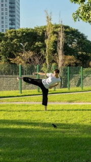 Martial artist performing a high kick outdoors
