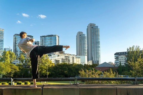 A focused Taekwondo practitioner against a modern city skyline