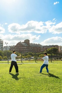 Two young men performing martial arts forms in a city park