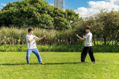 Two young men prepare to start a taekwondo fight outdoors