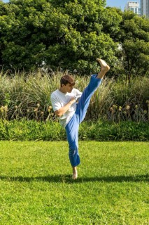 Young man performing a Taekwondo front kick outdoors