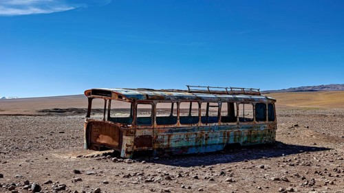 A rusty bus stands in a lonely desert landscape under a clear blue sky, An old Bus at the Border