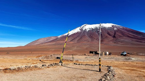 Border area in a treeless desert landscape with a snow-capped mountain and clear blue sky, The