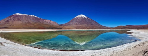 Broad mountain backdrop with two snow-covered peaks reflected in a calm lake, The Laguna Colorada