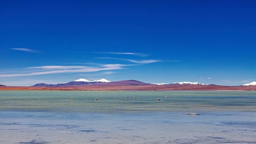Vast landscape with a clear lake and snow-capped mountains under a blue sky, The landscape of the