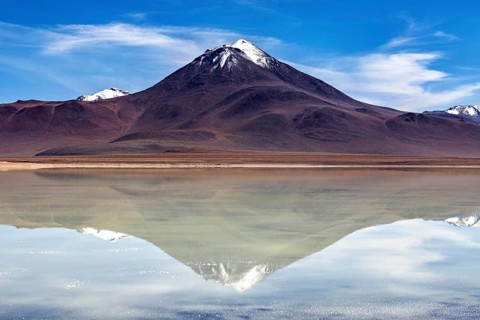 Majestic volcano reflected in a calm lake under a radiant sky, The Laguna Colorada in Bolivia