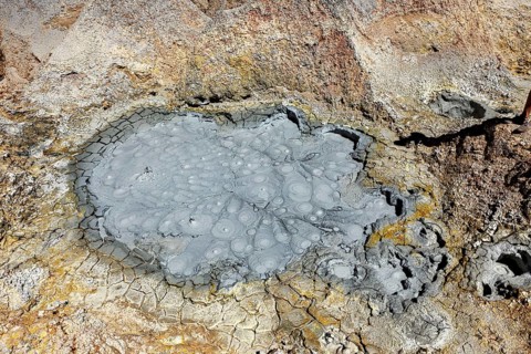 Cracked, grey crater floor with mud bubbles and geological structures, The mud volcanoes and