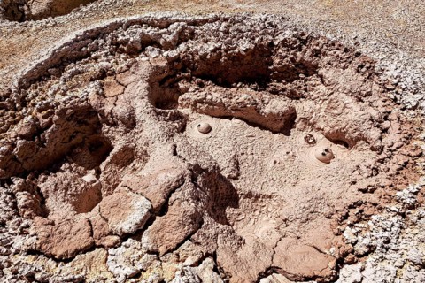 Red, cracked crater with muddy bubbles in a barren environment, The mud volcanoes and fumaroles on