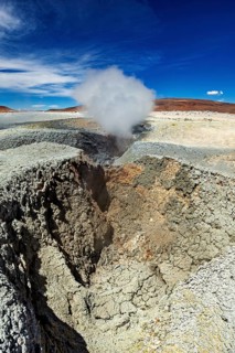 Large crater with steaming geyser in a rocky desert landscape, The mud volcanoes and fumaroles on